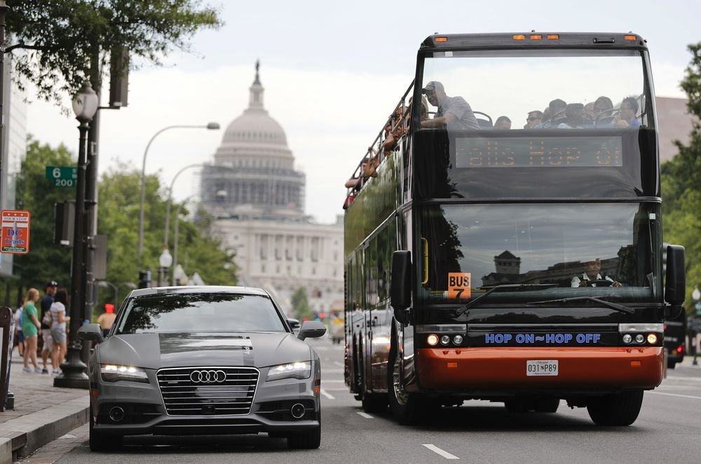 In this July 15, 2016, photo, a double decker tour bus drives by an Audi self driving vehicle parked on Pennsylvania Avenue, near the Capitol in Washington. The federal government should be in charge of regulating self-driving cars rather than states since the vehicles are essentially controlled by software, not people, Obama administration officials said Sept. 19 as they laid out the broad outlines of their plans to help get the transformational technology safely onto the nationþÄôs roadways. (AP Photo/Pablo Martinez Monsivais)