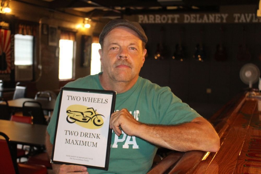Jim Parrott holds one of two signs in the Parrott Delaney Tavern in New Hartford that states the bars policy when it comes to serving motorcyclists. Bud Wilkinson Republican-American  